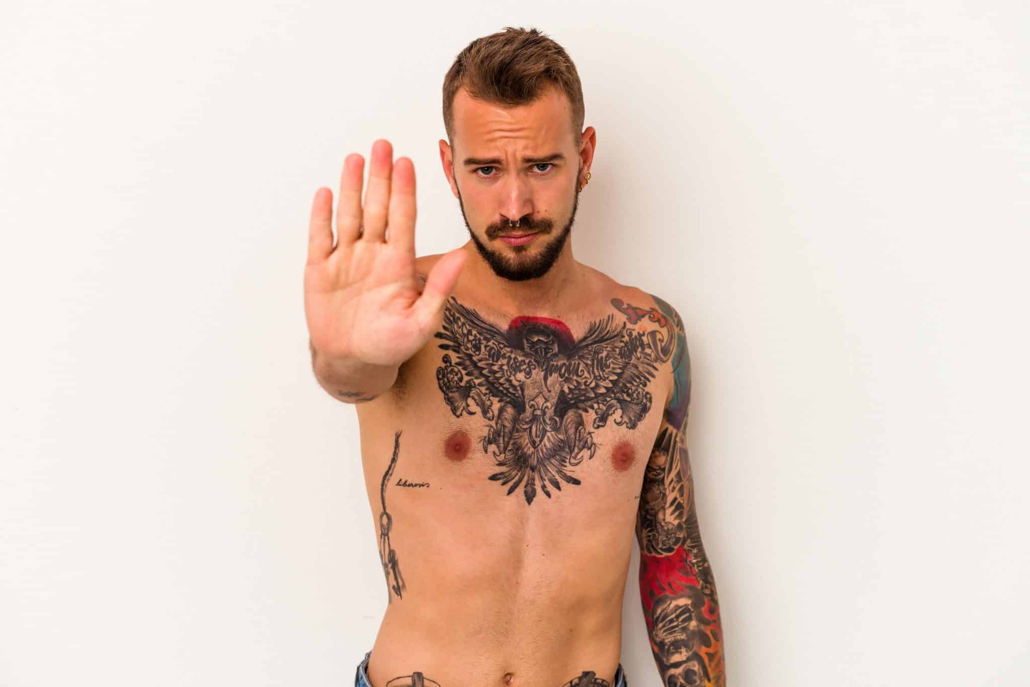 Billede af mand med tattoo der signalerer stop med hånden