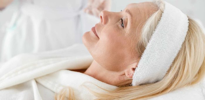 Beautiful Caucasian mature woman with closed eyes in cosmetology center during beauty treatment