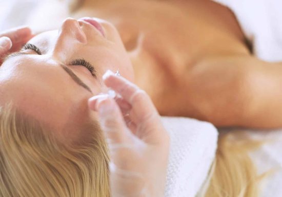Beautiful woman doing facial massage in a spa salon.