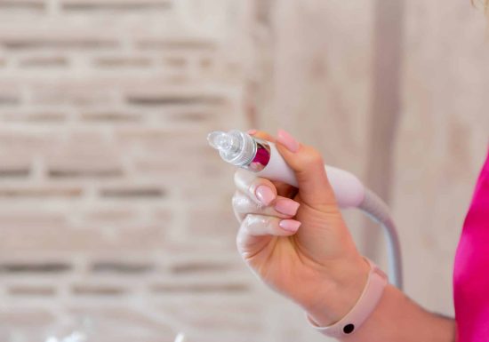 Photo of the Dermapen apparatus in the hands of a beautician. Non-injection mesotherapy procedure. Cosmetic apparatus for lifting and mesotherapy...